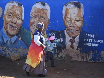 na donna cammina accanto al murale di Nelson Mandela a Soweto, Johannesburg, dove vive l'ex presidente.