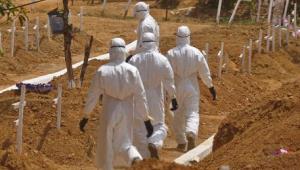 FILE- In this file photo dated Wednesday, March 11, 2015, health workers walk inside a new graveyard for Ebola victims, on the outskirts of Monrovia, Liberia. Despite the drop in reported Ebola cases, Dr. Bruce Aylward, leading WHOs Ebola response, declared Friday April 10, 2015, that its too early for World Health Organization to downgrade the global emergency status of the biggest-ever Ebola outbreak in Africa. (ANSA/AP Photo/Abbas Dulleh, FILE)