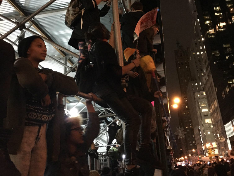 Alcune persone arrampicate su ponteggi nei pressi della Trump Tower per fotografare la situazione