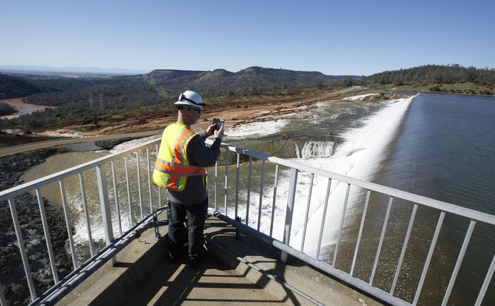 Jason Newton del Dipartimento per le risorse idriche della California scatta una foto all'acqua che scorre attraverso lo sfioratore principale e quello d'emergenza (AP Photo/Rich Pedroncelli) Fonte: ANSA